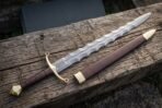 Twenty inch flame profile Damascus blade above a brass crossguard finished with ring finials