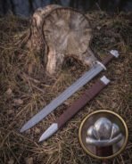 Valknut hilt viking sword and brown leather scabbard laid on woodland floor before a cut stump, the Vegvisir etched Damascus blade and lobed steel pommel in view