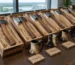 Row of hand forged hatchets in wooden gift crates with a horn tankard on a conference table